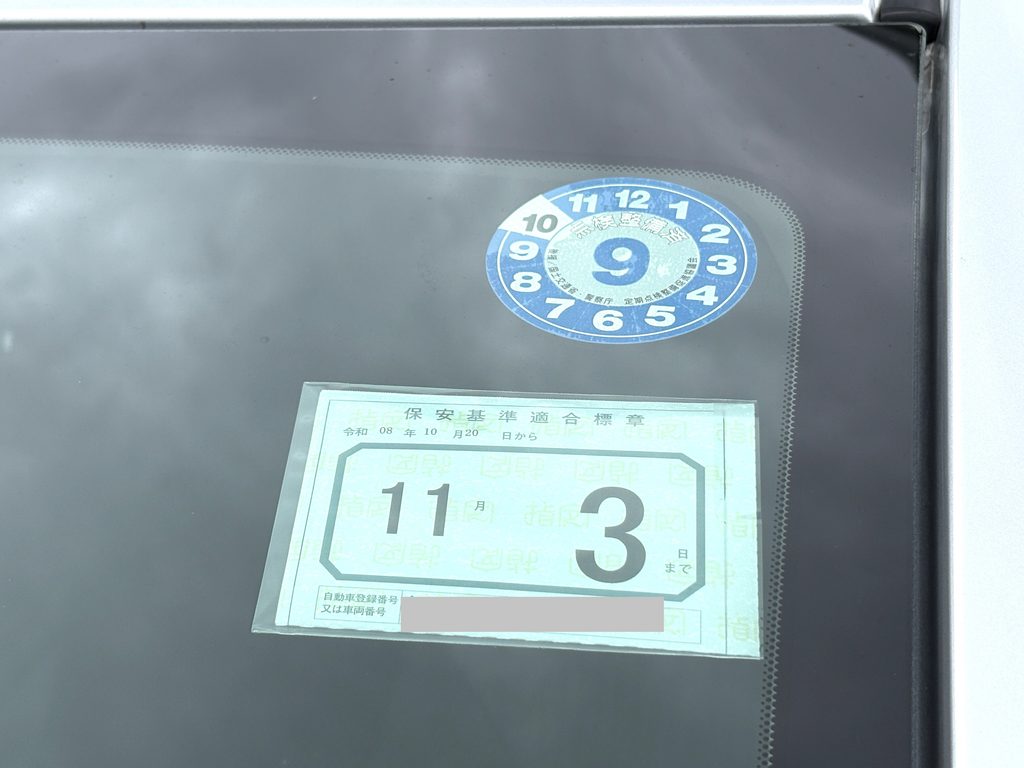 車のフロントガラスに貼られた保安基準適合標章と車検ステッカー